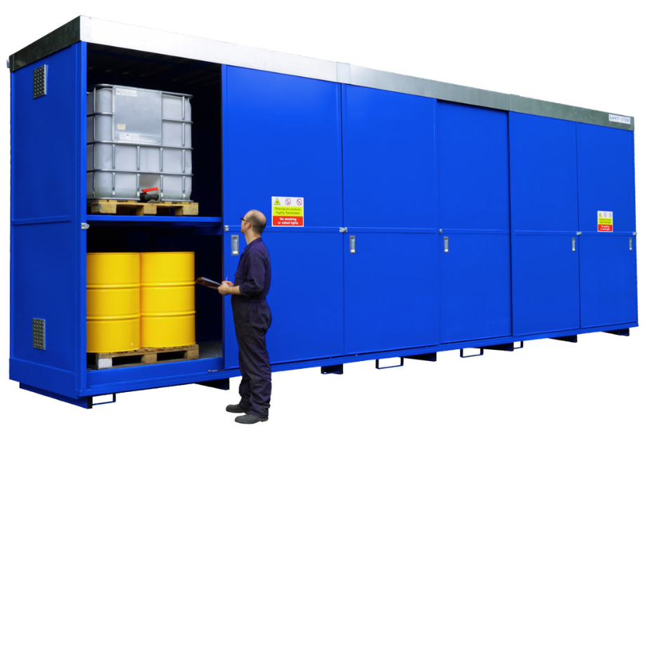 large blue storage unit with IBCs stored on the top shelf and yellow drums stored on the bottom shelf, with a man assessing the unit