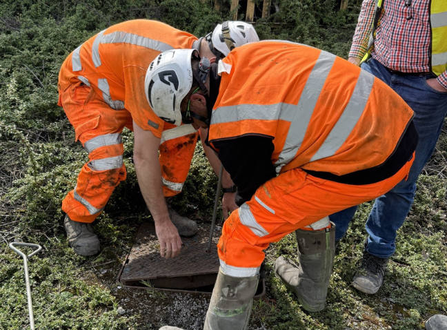 thumbnail image of a case study showing two men in orange hi vis lifting a drain cover

