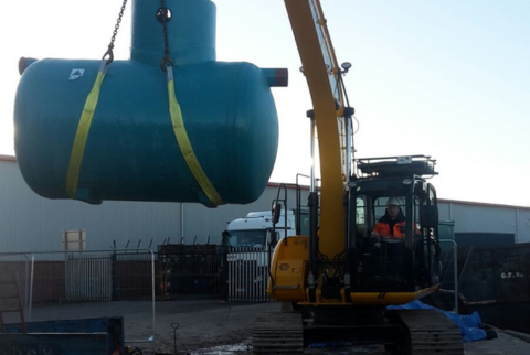 small blue interceptor being lifted by an excavator before being lowered into ground