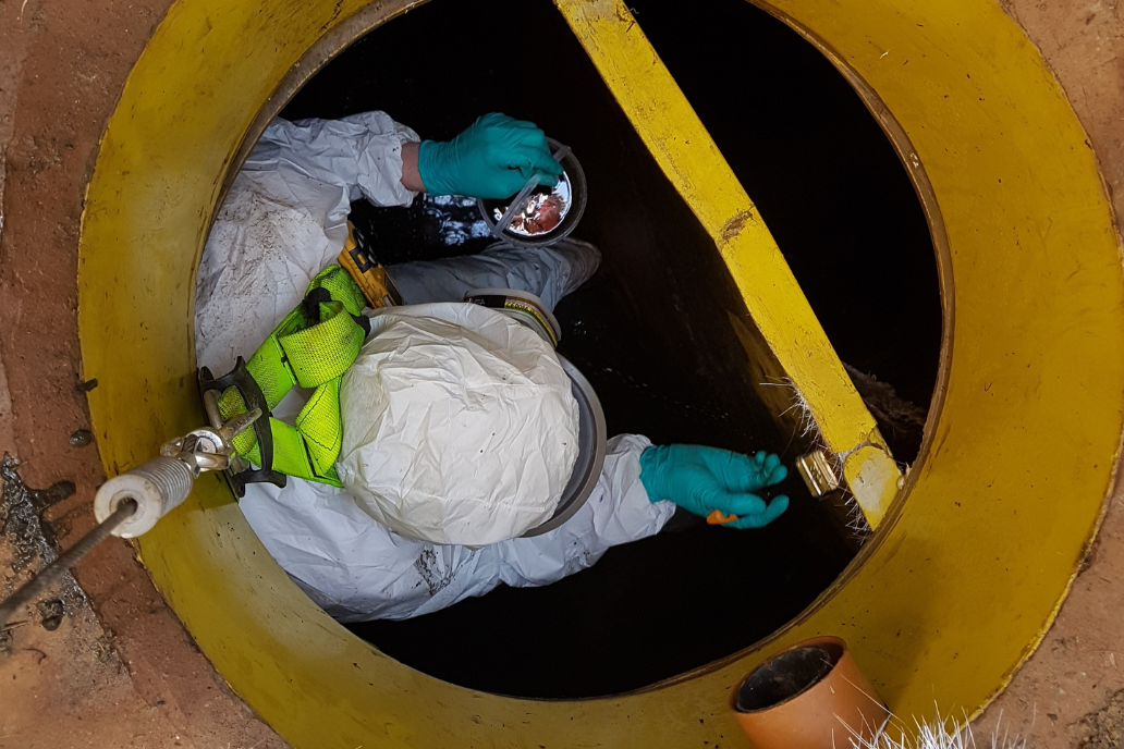 field engineer wearing full PPE within an interceptor conducting repairs through confined space entry
